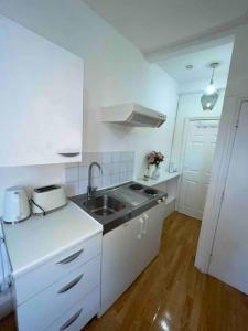a white kitchen with a sink and a stove at Private Studio Flat close to Central London with Smart TV and workspace in London