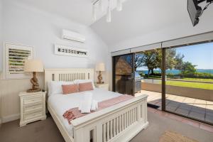a bedroom with a white bed and a large window at A Fisherman's Rest in Nelson Bay