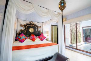 a bedroom with a canopy bed with colorful pillows at Quinta Las Acacias Hotel Boutique in Guanajuato