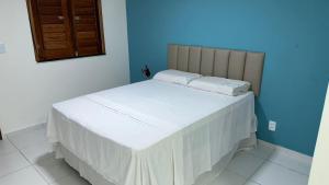 Cama blanca en habitación con pared azul en Pousada Maré Forte en Cascavel