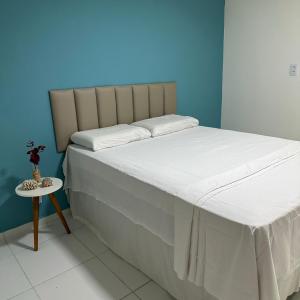 Pousada Maré Forte في كاسكافل: غرفة نوم بسرير كبير وطاولة جانبية