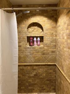 Una ducha de ladrillo con dos botellas rosas en un estante en Forks Fir House en Forks