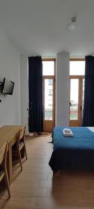 sypialnia z łóżkiem, stołem i oknami w obiekcie Get Cozy w Porto
