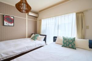 two beds in a room with a window at Haneda Lex Apartment in Tokyo