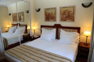 a hotel room with two beds and two mirrors at Vila Alba Resort in Carvoeiro