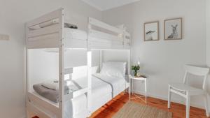 a white bunk bed in a white room with a desk at Kangaroo Cottage in Currarong