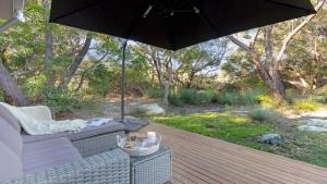 a patio with a couch and an umbrella on a deck at Kangaroo Cottage in Currarong +14 photos
