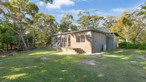 a small house in the middle of a yard at Kangaroo Cottage in Currarong +14 photos