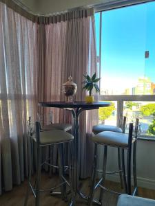 a table and chairs in a room with a window at Aconchegante Apartamento decorado e mobiliado in Cascavel +30 photos