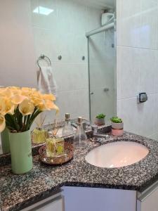 a bathroom counter with a sink and flowers on it at Aconchegante Apartamento decorado e mobiliado in Cascavel