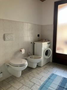 een badkamer met een toilet, een wastafel en een wasmachine bij UN PASSO DAL CASTELLO in Barolo