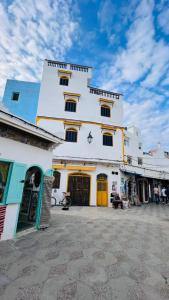 a large white building with yellow doors on a street at Dar Yema in Asilah