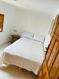 a bedroom with a large bed with a wooden door at Dar Yema in Asilah