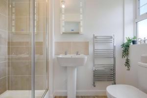 een witte badkamer met een wastafel en een douche bij Detached House with Free Parking, Super-Fast Wifi and Smart TV with Netflix by Yoko Property in Northampton