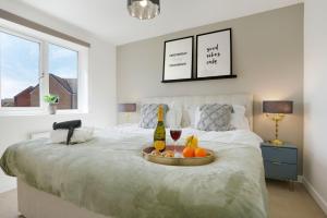 a bed with a tray of fruit and a bottle of wine at Detached House with Free Parking, Super-Fast Wifi and Smart TV with Netflix by Yoko Property in Northampton