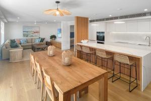 una cucina e un soggiorno con tavolo in legno di The Cove Noosa - Apartment 18 a Noosa Heads