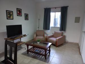 uma sala de estar com uma televisão e duas cadeiras e uma mesa em Duplex 80 mts cubiertos con garaje em San Fernando del Valle de Catamarca