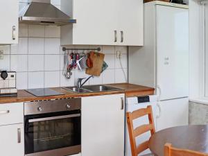 cocina con armarios blancos, fregadero y mesa en Holiday home Åskloster II, en Åskloster