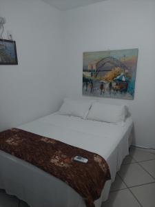 1 cama en una habitación con un cuadro en la pared en Apartamento na Praia dos Anjos, en Arraial do Cabo
