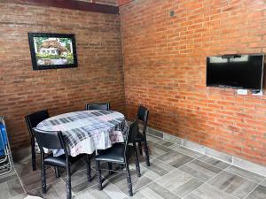 einen Tisch mit Stühlen und einen TV an einer Backsteinwand in der Unterkunft Cabañas las brisas in La Banda