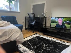 a bedroom with a tv with a man on it at The Grande Residence - Close to Central London & Next to Northfield Tube station in Hanwell