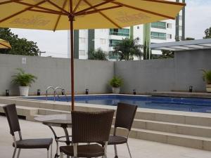 a table and chairs with an umbrella next to a pool at Flat Bristol 911 in Goiânia