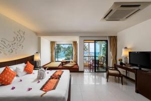 a hotel room with a bed and a tv and a bedroom at Patong Paragon Resort & Spa SHA Extra Plus in Patong Beach