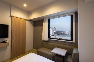Zimmer mit einem Fenster, einem Sofa und einem TV in der Unterkunft Fourz Hotel Kintetsu Osaka-Namba in Osaka