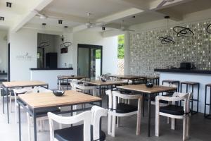 a restaurant with wooden tables and white chairs at Amazing Lombok Resort in Selong Belanak