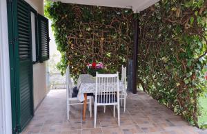 una mesa y sillas en un patio con una pared cubierta de hiedra en House Maja en Jadrija
