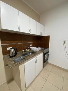 Una cocina con gabinetes blancos y encimera. en Monoambiente Centrico, en Santiago del Estero