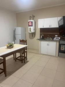 cocina con armarios blancos, mesa y TV en Monoambiente Centrico, en Santiago del Estero 2 fotos más