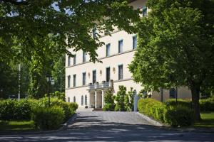 a large white building with a driveway at Bofors Hotel in Karlskoga