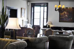 una sala de estar con sofás, sillas y una lámpara. en Bofors Hotel, en Karlskoga