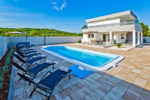 a swimming pool with chairs next to a house at Villa Blazen in Bogomolje