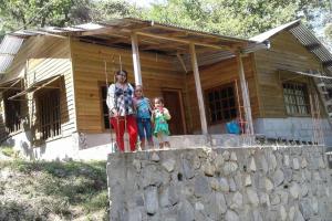 a woman and two children standing in front of a house at Mi rincón en la montaña. in La Ceiba
