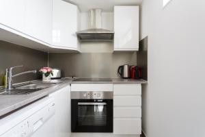 eine Küche mit weißen Schränken und einem schwarzen Backofen in der Unterkunft Maison de ville le blanc mesnil in Le Blanc-Mesnil