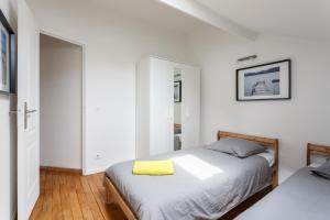 ein weißes Schlafzimmer mit 2 Betten und einem gelben Kissen in der Unterkunft Maison de ville le blanc mesnil in Le Blanc-Mesnil