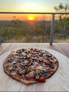 a pizza on a table with the sunset in the background at Gorge View Bush Retreat : Katherine NT in Katherine