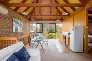 ein Wohnzimmer mit einem weißen Kühlschrank und einem Tisch in der Unterkunft Shearwater Beach House in Silverleaves in Cowes