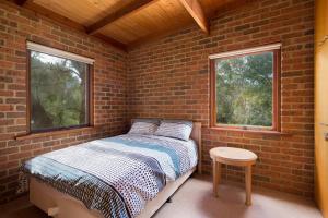 ein Backsteinzimmer mit einem Bett und zwei Fenstern in der Unterkunft Shearwater Beach House in Silverleaves in Cowes