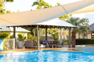 a patio with a pool and a large white umbrella at Seashells Broome in Broome