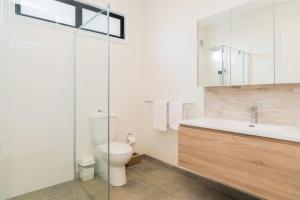 a bathroom with a toilet and a sink and a mirror at Beachcomber Sunset in Smiths Beach +19 photos