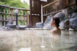 uma mulher parada numa piscina de água em Shima-Onsen Toshimaya em Nakanojo