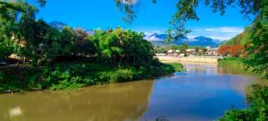a river with trees and mountains in the background at Ban Lakkham River View in Luang Prabang