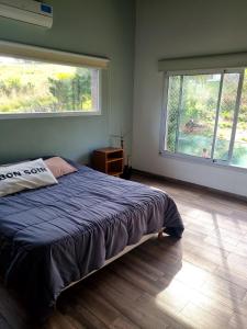 a bedroom with a large bed and two windows at Casa sierra de los padres in Sierra de los Padres