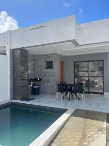 a house with a swimming pool and a dining room at Carapibus casa de praia 02 in Conde