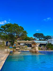 una piscina con un puente de piedra junto a un complejo en Pousada Serra de São Thomé, en São Thomé das Letras