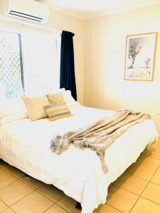 a bedroom with a white bed with a window at Trinity Beach Sea Breeze 3 Bedroom Apartment in Trinity Beach