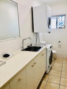 a kitchen with a sink and a washing machine at Trinity Beach Sea Breeze 3 Bedroom Apartment in Trinity Beach